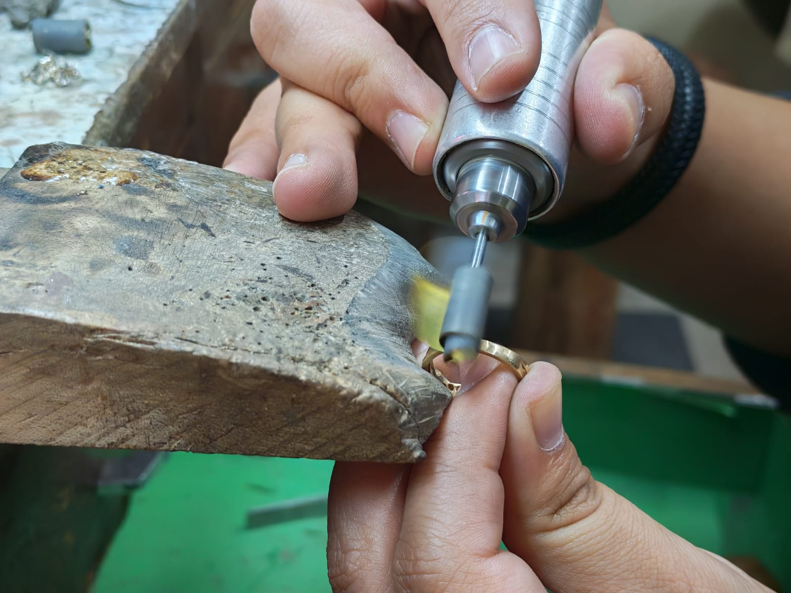 Manos del orfebre reparando una joya en la mesa de trabajo